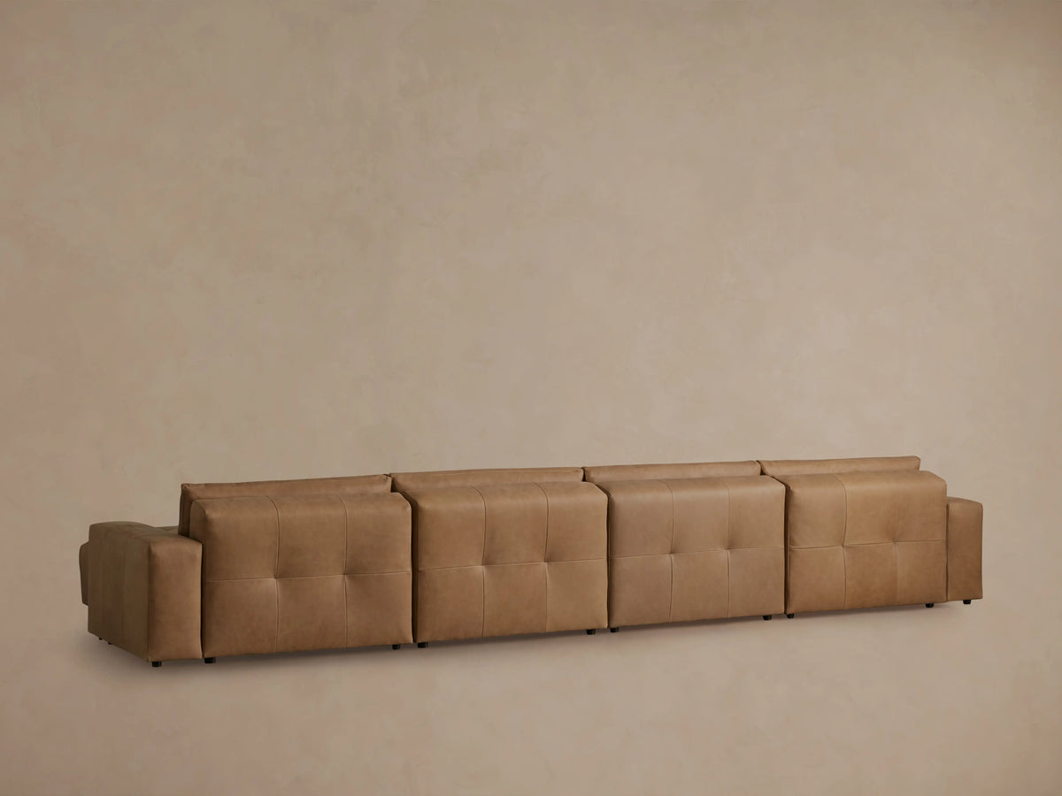 Keegan Leather Six-Piece Sectional in brown leather, showcasing tufted seat cushions and smooth backrests in a cozy setting.