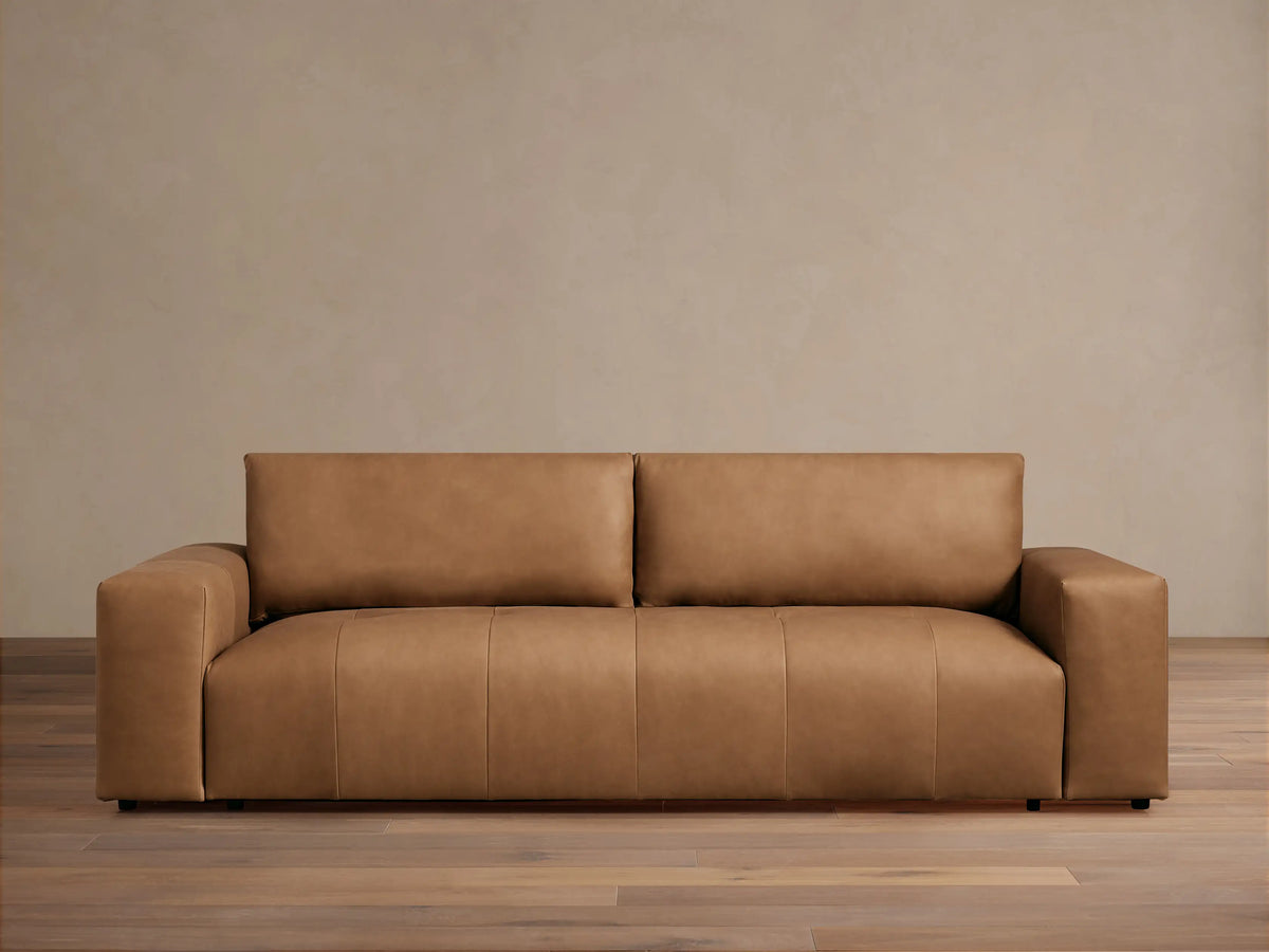 Keegan Leather Sofa, a modern, sleek tan leather sofa with block arms, centered against a light beige wall and wood floor.