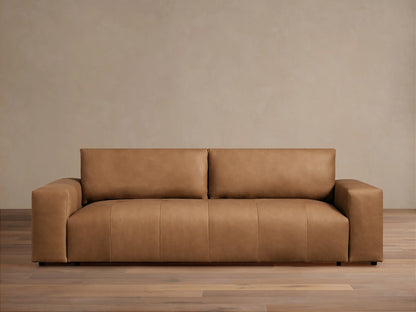 Keegan Leather Sofa, a modern, sleek tan leather sofa with block arms, centered against a light beige wall and wood floor.