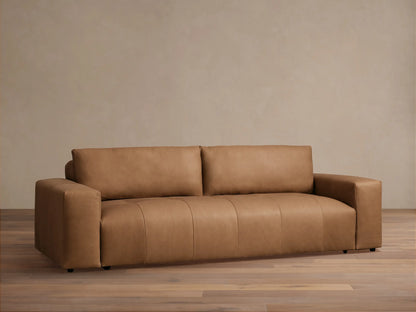 Keegan Leather Sofa, a modern, sleek tan leather sofa with block arms, centered against a light beige wall and wood floor.