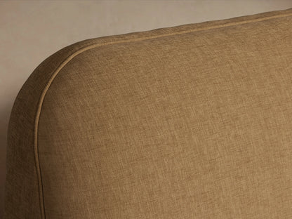 Kinnan Bed headboard in beige fabric with smooth, rounded edges and fine stitching detail, shown against a plain background.