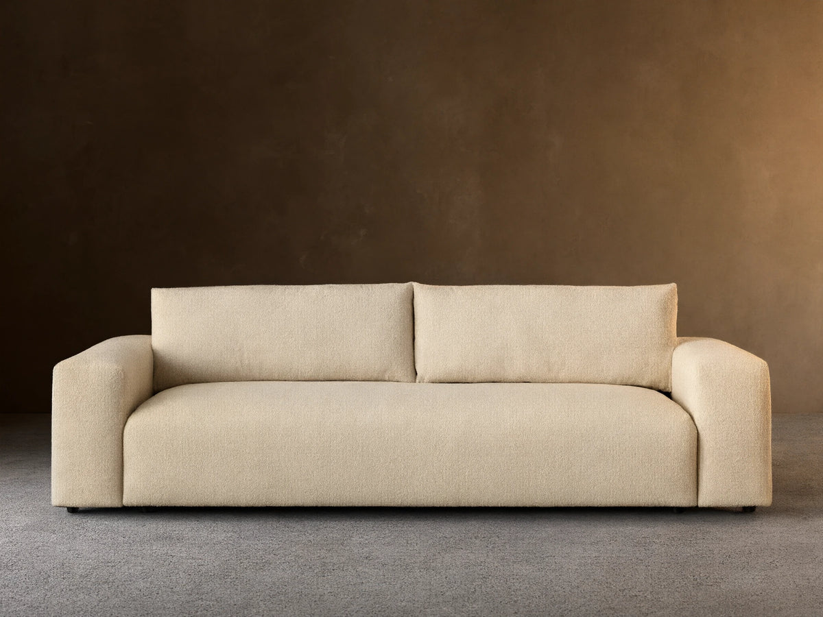 Keegan Tailored Sofa, light beige textured fabric. Modern style, two back cushions, wide square arms, on a wooden floor.