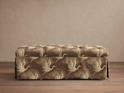 Front view of the brown Liddie Bench with a tufted top, skirted base, and light brown crane bird pattern.