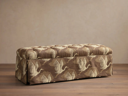Front view of the brown Liddie Bench with a tufted top, skirted base, and light brown crane bird pattern.