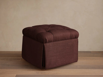 Front view of the burgundy Liddie Square Ottoman with a tufted top and pleated skirt.