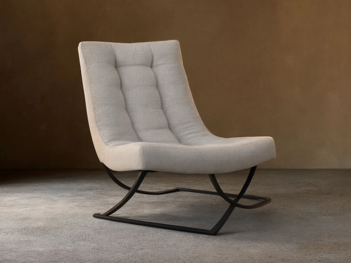 Lloyd Chair: Modern light grey fabric chair with a tall, padded back and seat, on a unique black metal X-frame base, angled on wood floor.