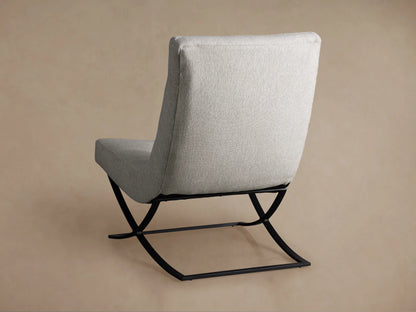 Light gray tufted Lloyd Chair, angled close-up, showing textured fabric and black metal base on a light background.