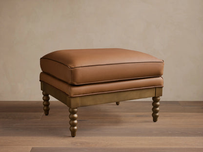Front view of the brown Milly Leather Ottoman with piped cushions and turned wood legs.