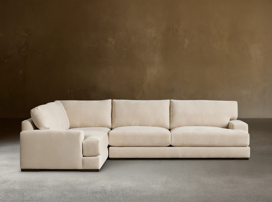 Beige Norwalk two-piece sectional on wooden floor, featuring plush cushions and L-shaped design against a neutral wall.