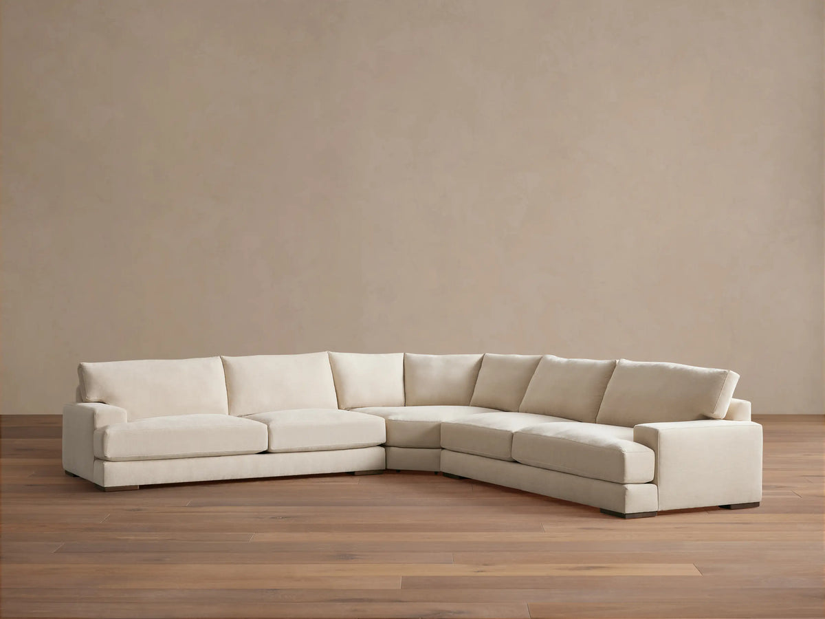 Norwalk Three-Piece Corner Wedge Sectional in beige fabric. L-shaped design on wooden floor, against a light brown wall.