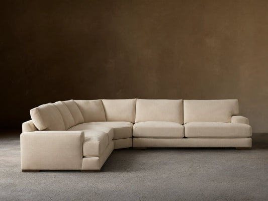 Norwalk Three-Piece Corner Wedge Sectional in beige fabric. L-shaped design on wooden floor, against a light brown wall.