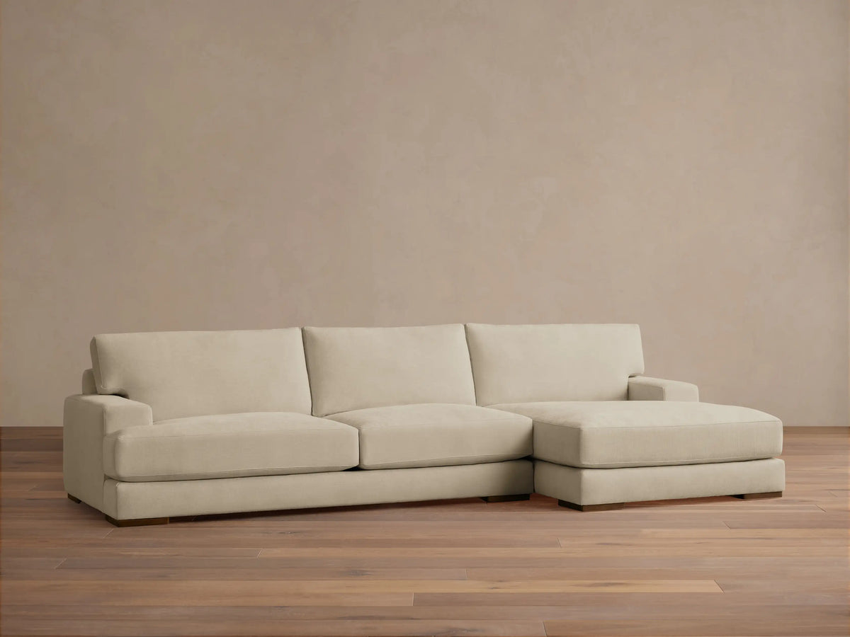 Norwalk Two-Piece Chaise Sectional in beige fabric, featuring plush cushions and a right-facing chaise, against a neutral wall.