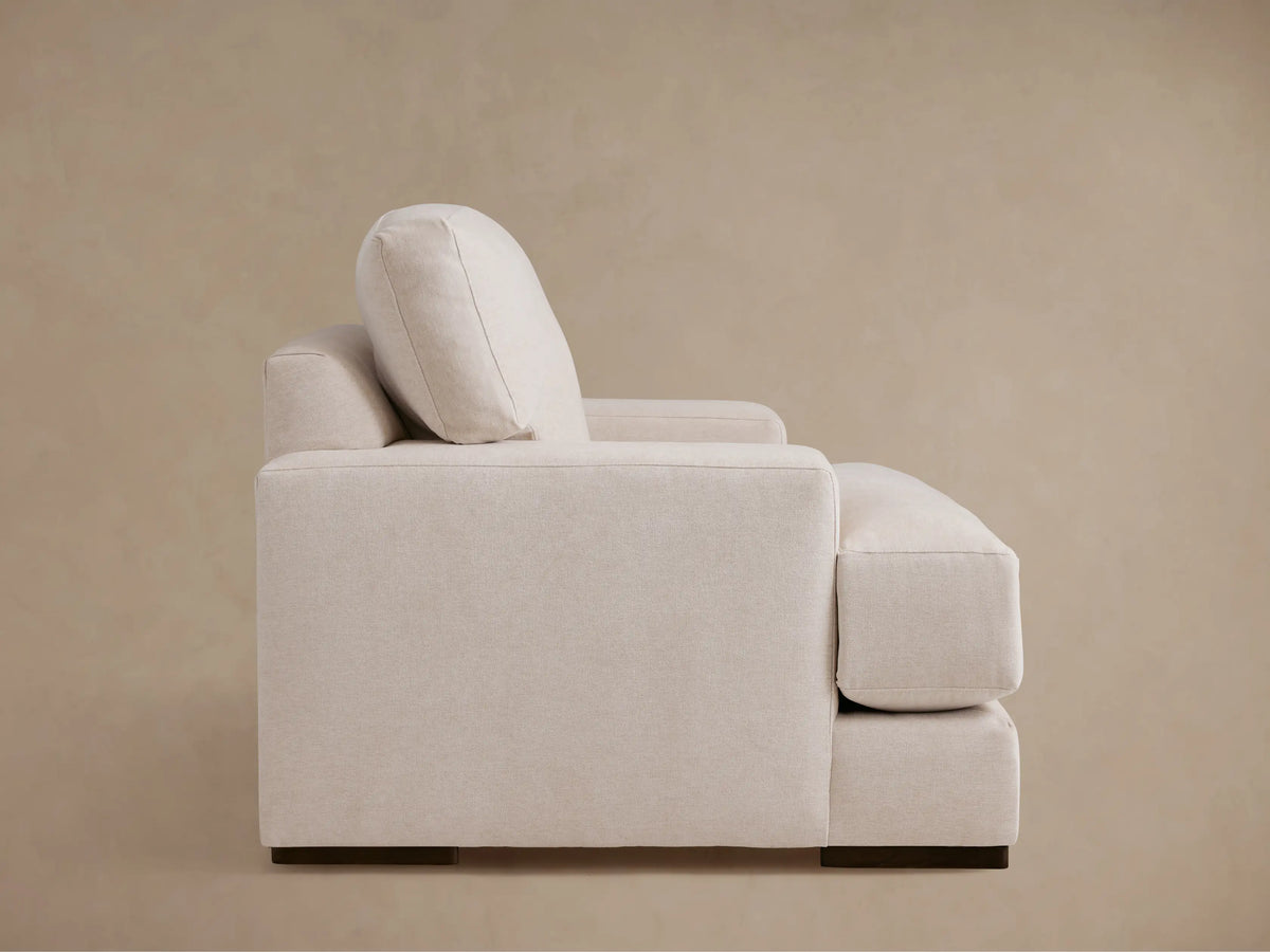 Beige Norwalk Chair with plush, cushioned backrest, wide armrests, and soft fabric upholstery. Chair angled slightly to the left.