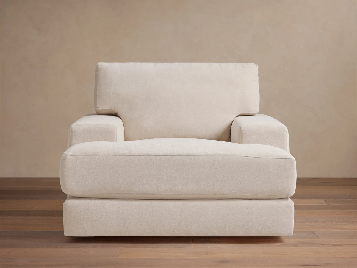 Cream-colored Norwalk Swivel Chair with plush seat and backrest, thick armrests, set on wooden floor against a beige wall.