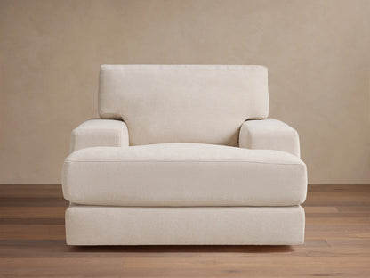 Cream-colored Norwalk Swivel Chair with plush seat and backrest, thick armrests, set on wooden floor against a beige wall.