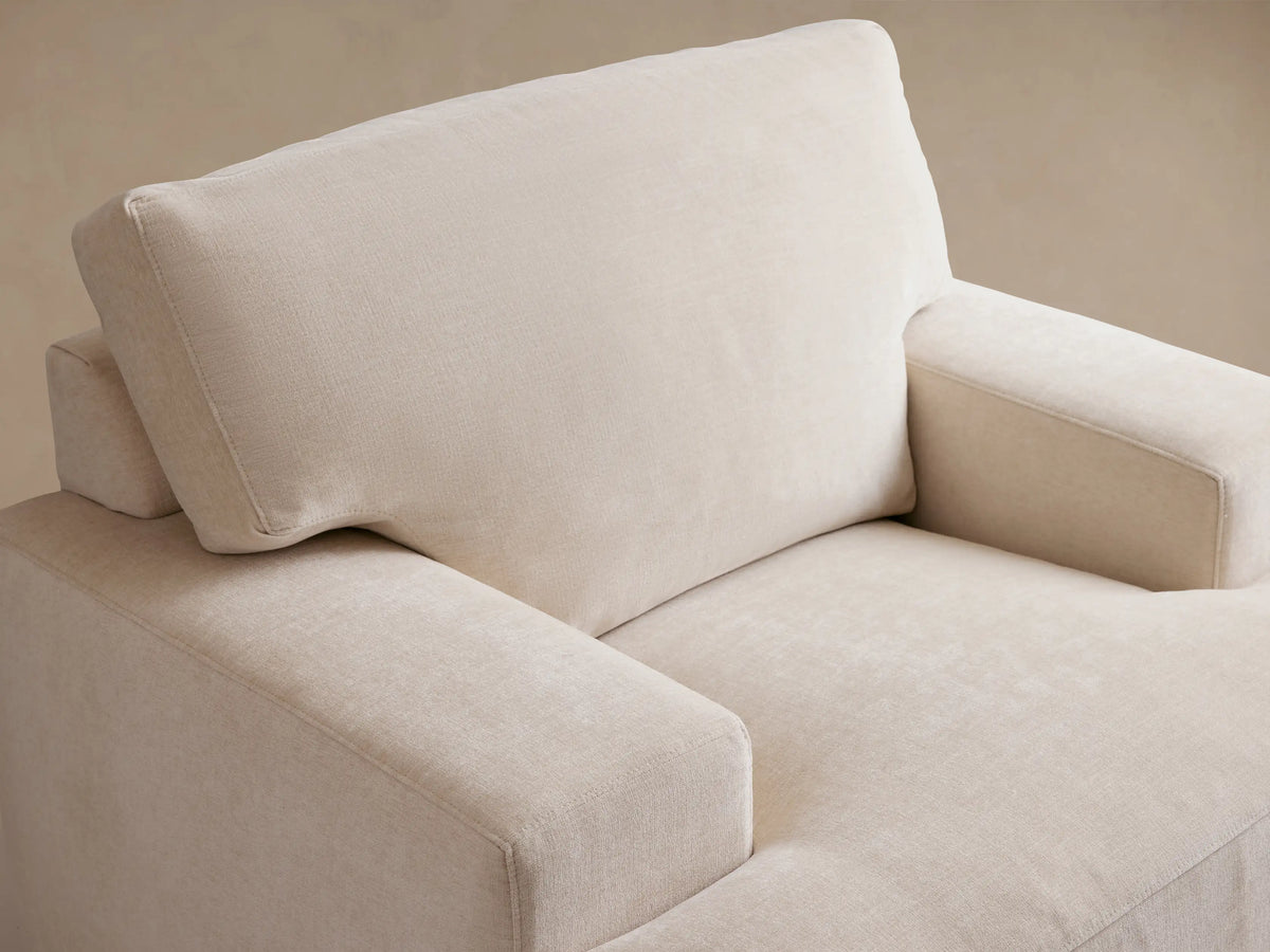 Norwalk Swivel Chair in beige fabric, featuring a square shape with plush cushioned seating and armrests, set against a hardwood floor.