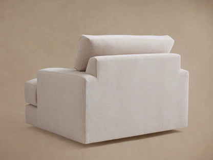 The Norwalk Swivel Chair shown from the side, featuring light beige upholstery, wide armrests, and plush cushions against a neutral background.