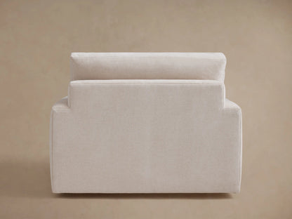 A beige Norwalk Swivel Chair with a minimalist design, featuring plush cushions and a square backrest, shown from a rear angle.