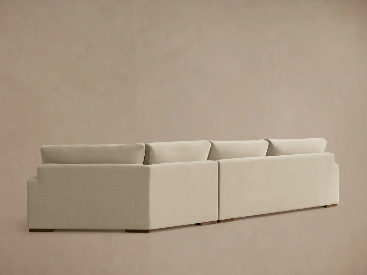 A close-up of the Norwalk Two-Piece Cuddle Chaise Sectional in light beige fabric, showing the plush seat and backrest with firm armrest.