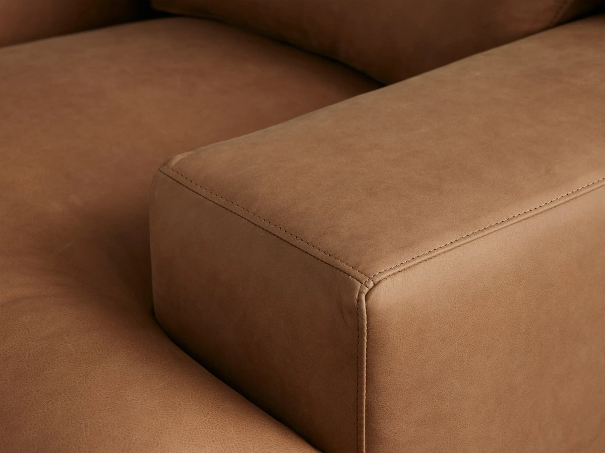 Tan Norwalk Leather Chair with broad arms, plush seat, and backrest. Set on a wooden floor, against a neutral wall backdrop.