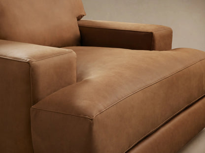 Norwalk Leather Swivel Chair in tan leather, front view. Features plush cushions, wide armrests, and a solid base on wooden floor.