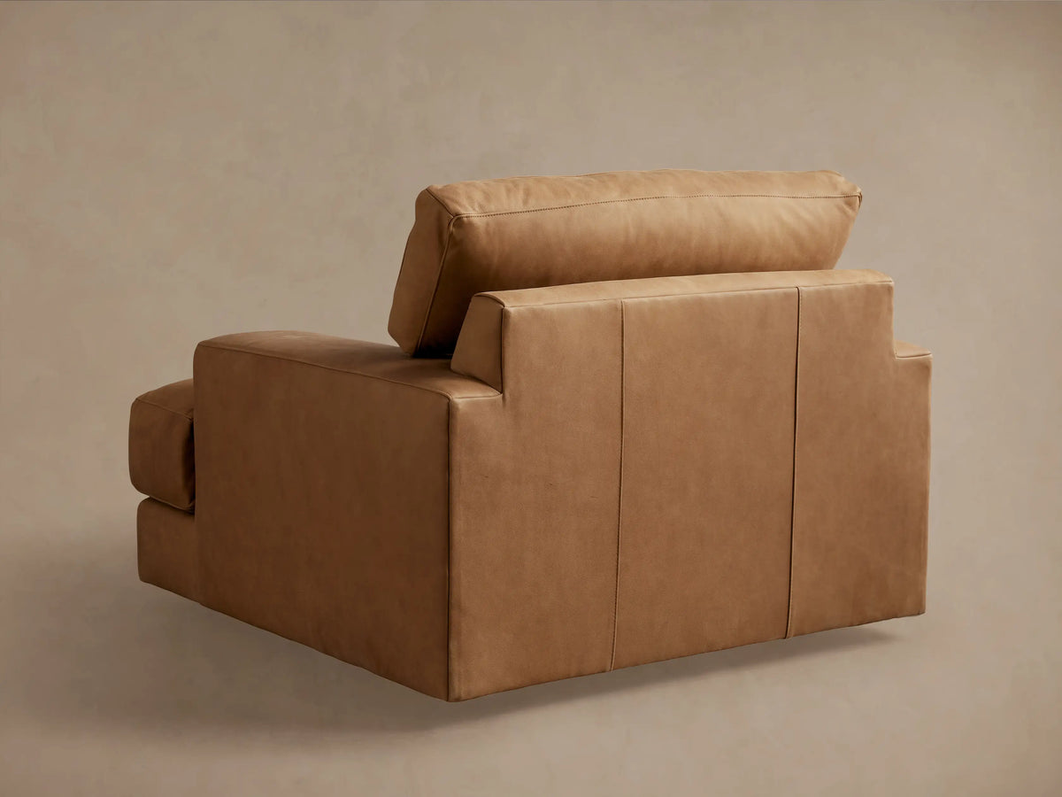 Norwalk Leather Swivel Chair in a warm brown hue, featuring plush, smooth leather upholstery, wide armrests, and a deep seat.