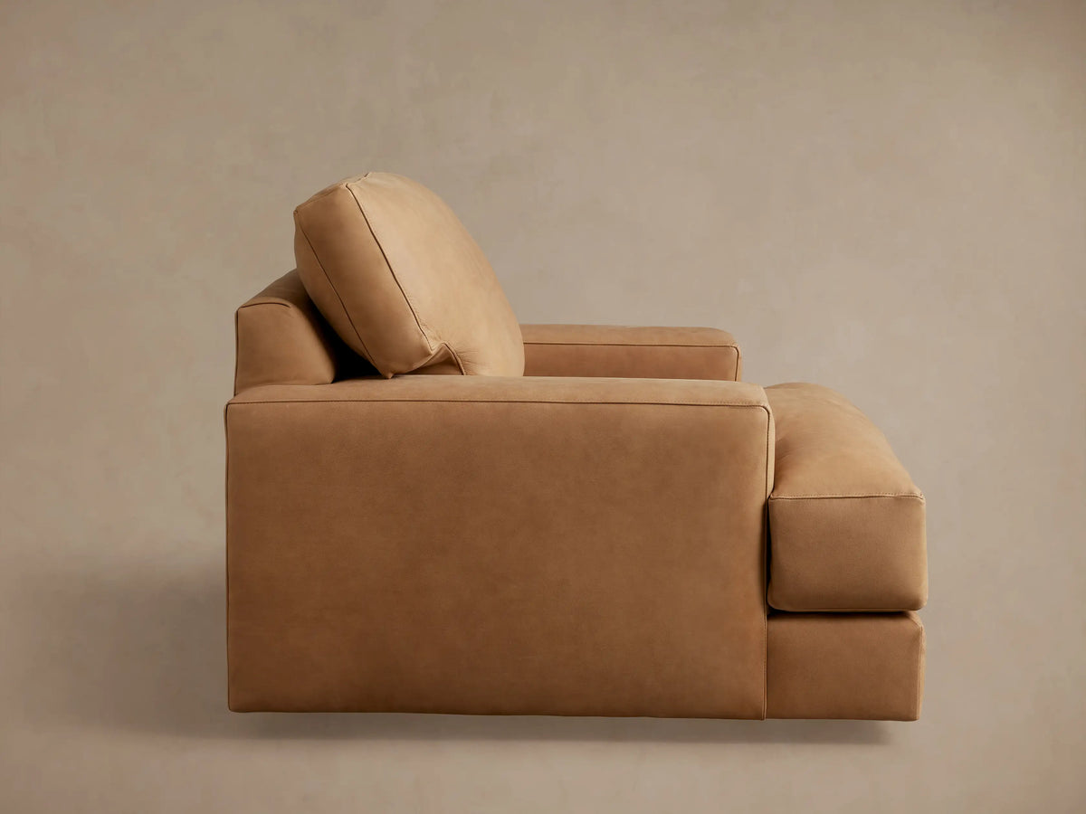 Back view of Norwalk Leather Swivel Chair in tan leather, showcasing a plush backrest and slightly curved armrests, against a neutral background.