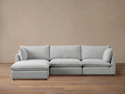 Front view of Owen Four-Piece Sectional in light grey Burbank Pepper textured fabric, chaise on left, against a beige wall, wooden floor.