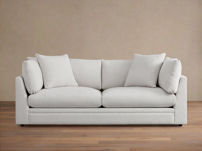 Pavo Sofa in Barbados Cream fabric, with plush cushions and clean lines. Placed on a wooden floor against a neutral wall.