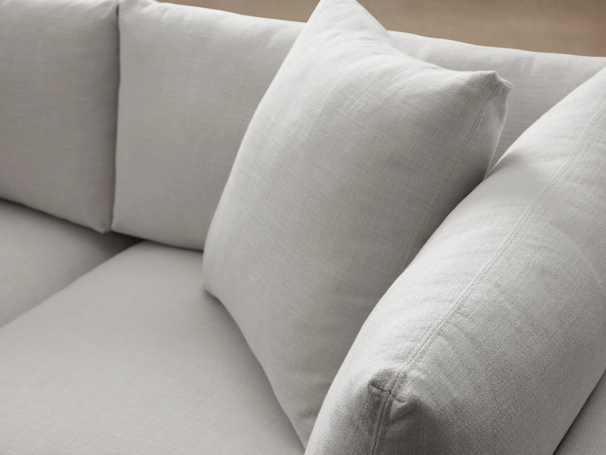 Pavo Sofa in Barbados Cream fabric, with plush cushions and clean lines. Placed on a wooden floor against a neutral wall.