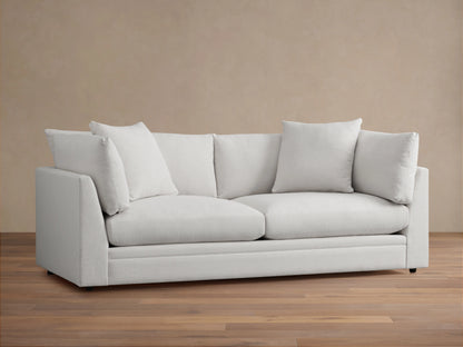 Pavo Sofa in Barbados Cream fabric, showing close-up of corner with plush seat and back cushions, smooth texture, and neutral color.
