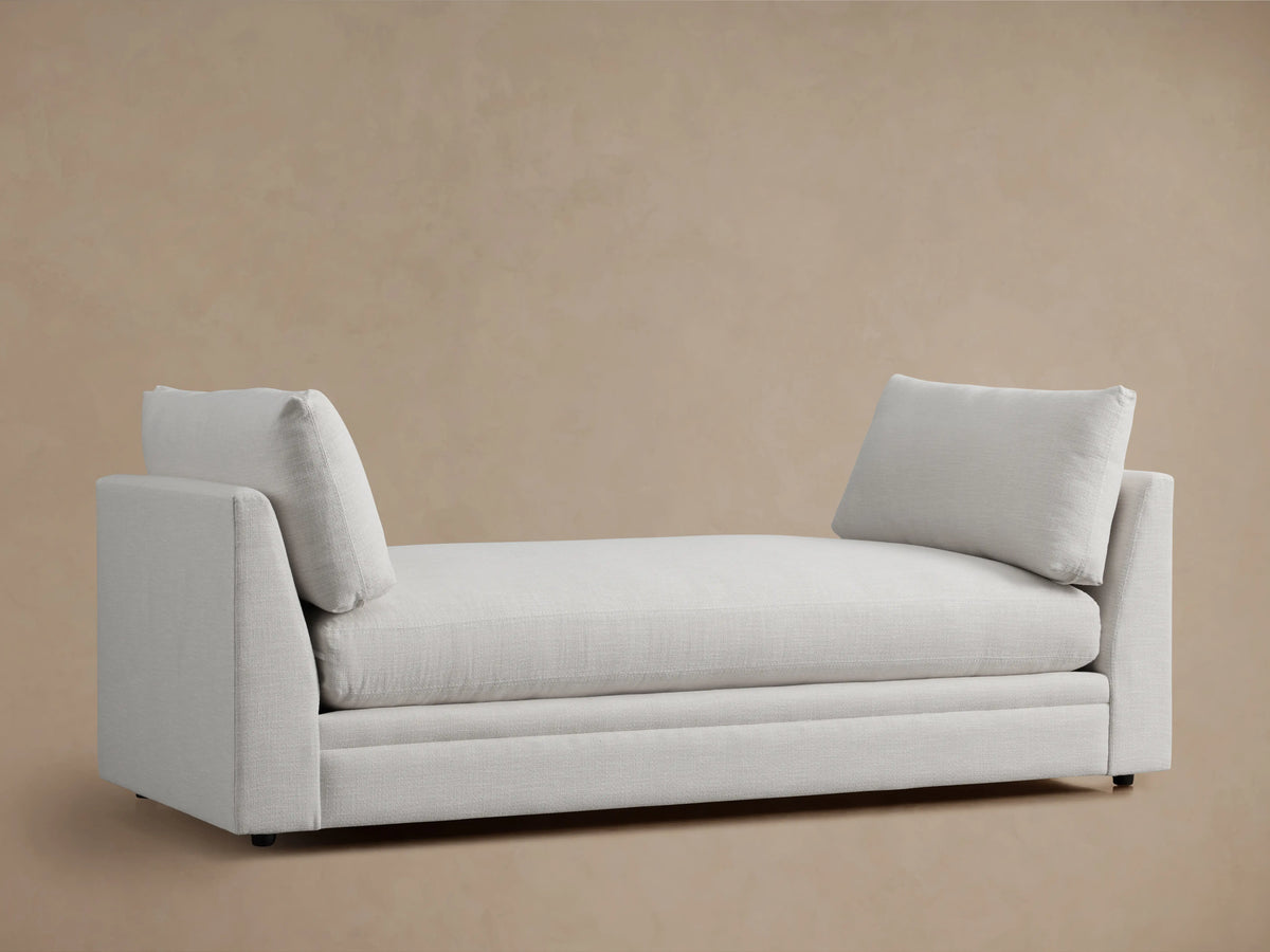 Pavo Daybed in Barbados Cream fabric with rectangular cushions on each end, featuring a sleek, minimalist design against a neutral background.
