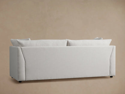 Pavo Trundle Sleeper Sofa in Barbados Cream fabric, featuring plush cushions and a sleek, angled armrest design on a soft beige background.
