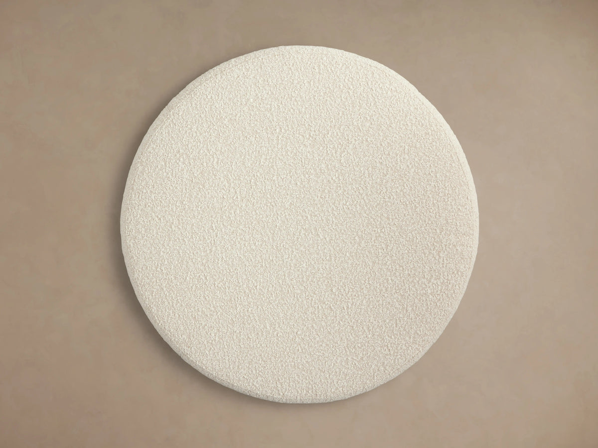 Ryles Plinth Ottoman in a circular shape with a textured cream fabric, displayed against a neutral background.
