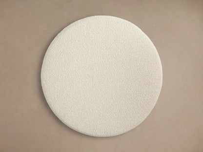 Ryles Plinth Ottoman in a circular shape with a textured cream fabric, displayed against a neutral background.