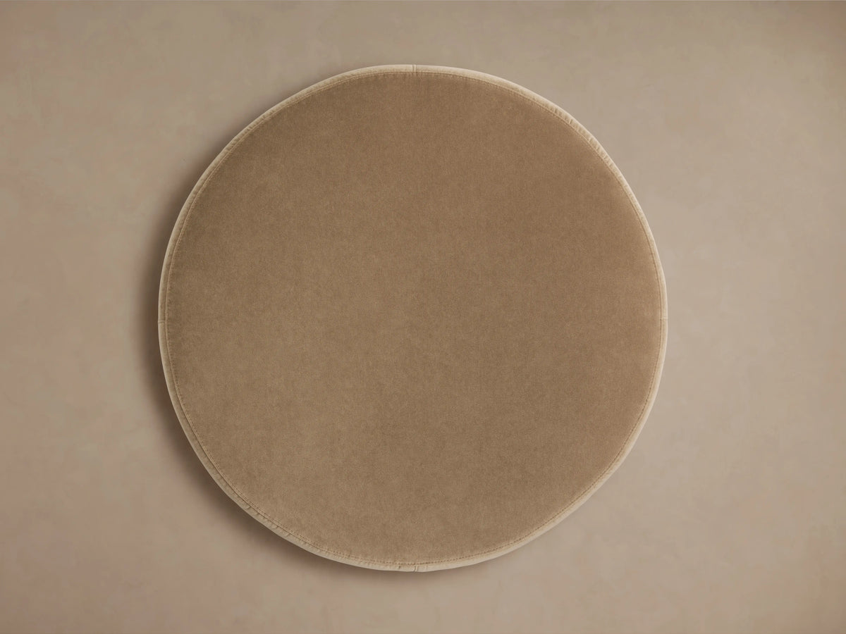 Smooth, circular Ryles Plinth Ottoman in light beige fabric, viewed from above, showcasing its plush, seamless surface.