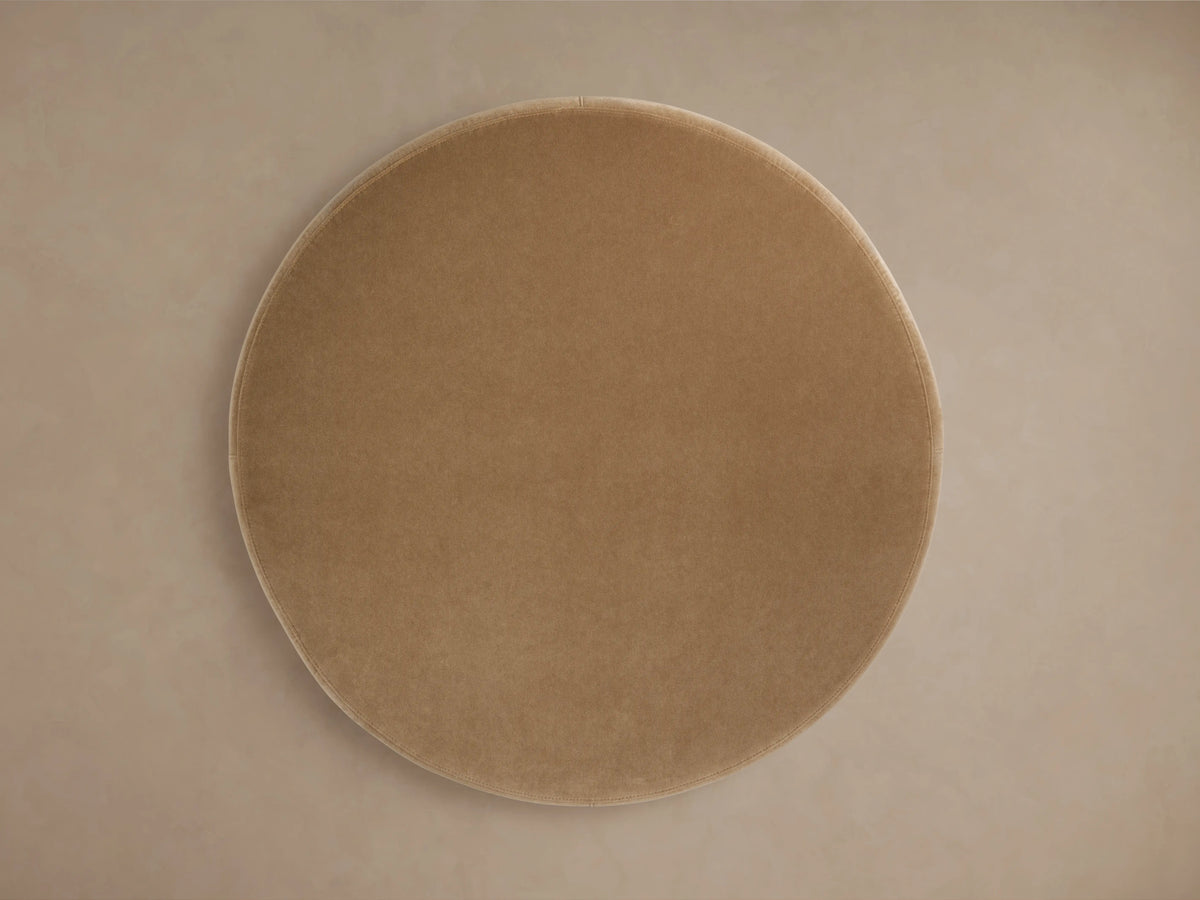 Circular Ryles Plinth Ottoman in light beige fabric. Viewed from above, showcasing its smooth, flat surface and neutral tone.