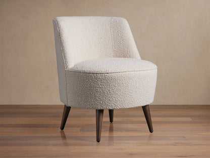 Ryles Chair, off-white boucle accent chair angled right, with curved back and dark tapered legs on wood floor.