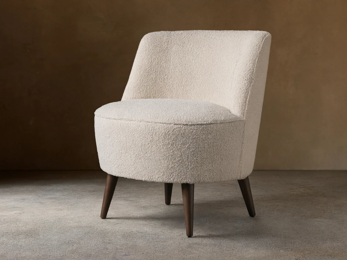 Ryles Chair, off-white boucle accent chair angled right, with curved back and dark tapered legs on wood floor.