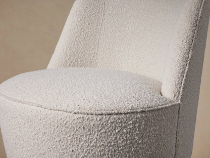 Front view of the Ryles Chair, an armless cream bouclv© upholstered chair with a curved back and dark tapered wood legs, on a wood floor.