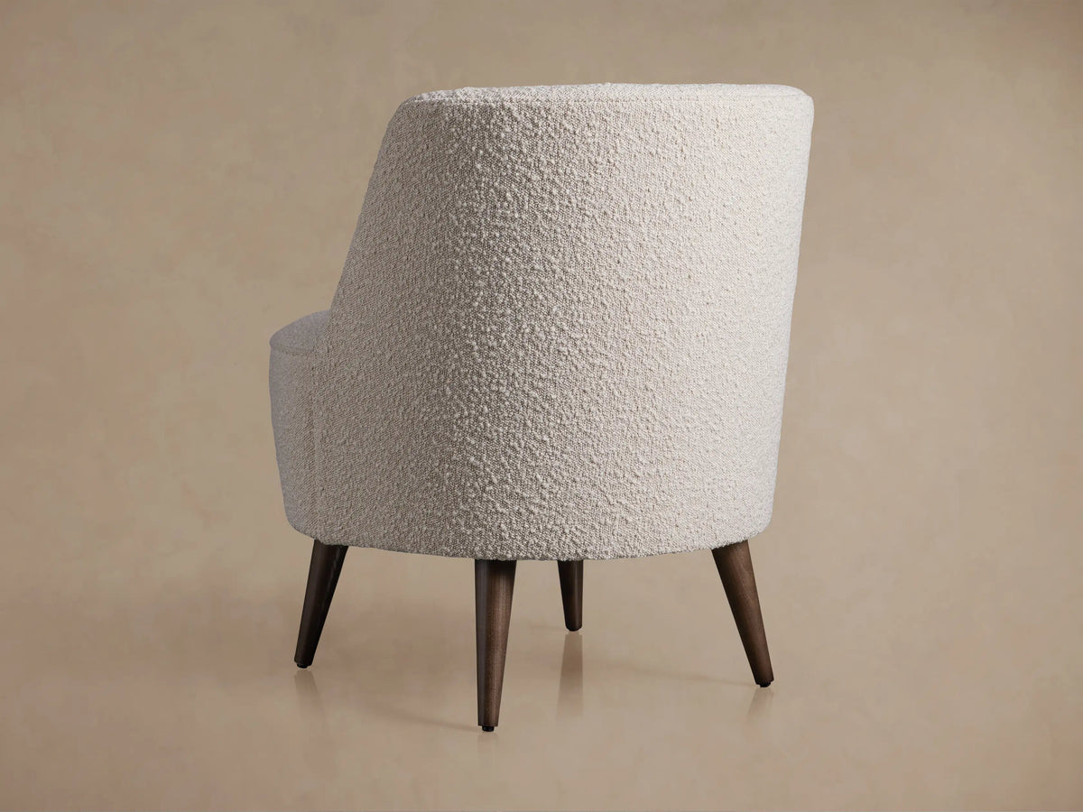 Close-up, angled view of a Ryles Chair upholstered in textured, light off-white boucle fabric with curved back and seat.