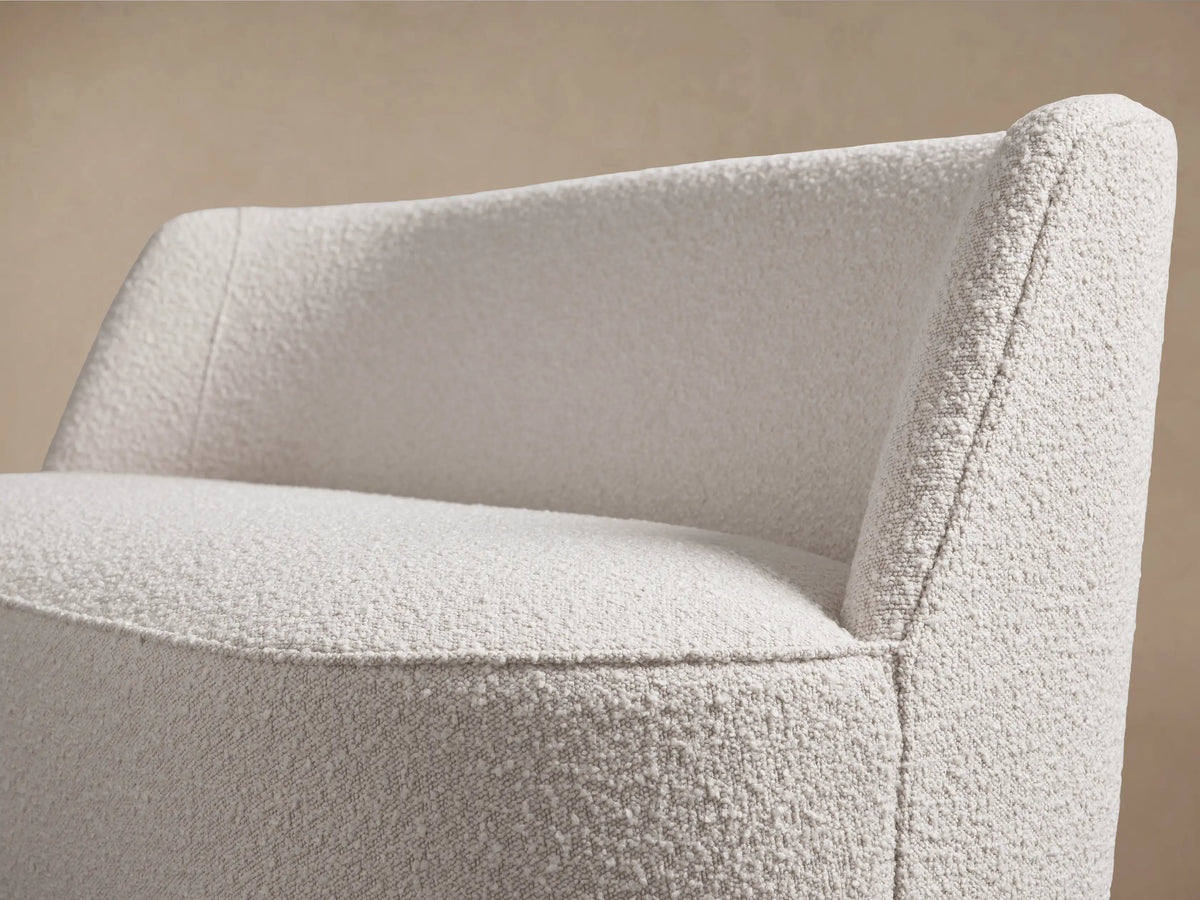 Ryles Tapered Leg Settee, a creamy white, textured bouclv© loveseat with curved back and dark tapered wood legs on wood floor.