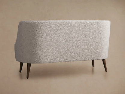 Close-up of Ryles Tapered Leg Settee's back and right arm, upholstered in light cream bouclv© fabric with visible stitching.