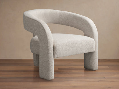 Light grey Mara Cutout Chair with textured fabric, modern curved arms and stout legs, angled on a wood floor.