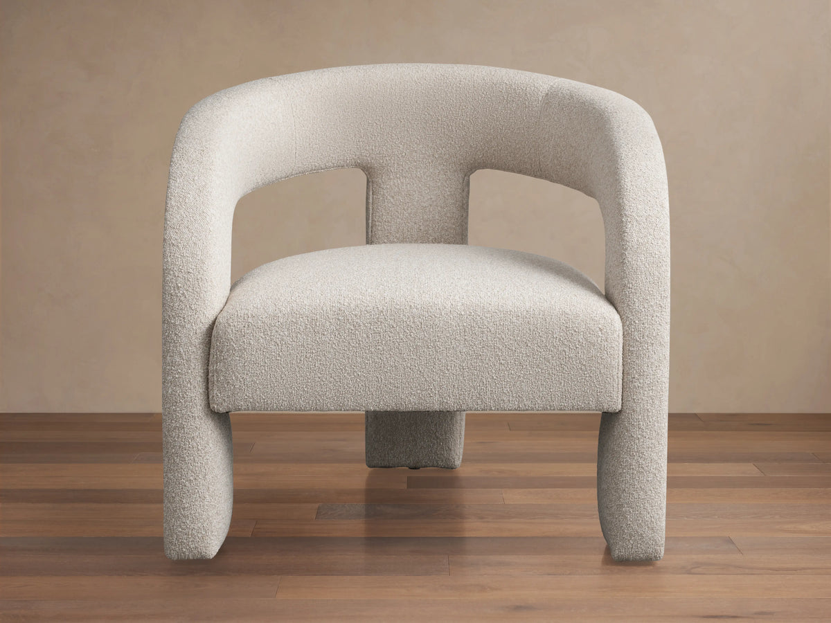 Front view of the Mara Cutout Chair, an ecru textured fabric chair with rounded arms and a modern cutout design.