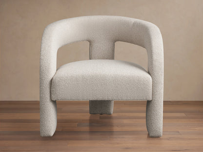 Front view of the Mara Cutout Chair, an ecru textured fabric chair with rounded arms and a modern cutout design.
