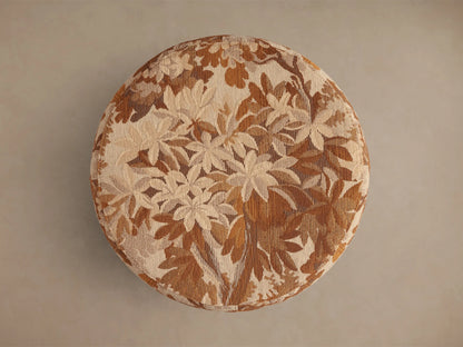 Top view of the round Ryles Ottoman, upholstered in a beige, cream, and brown floral jacquard fabric.
