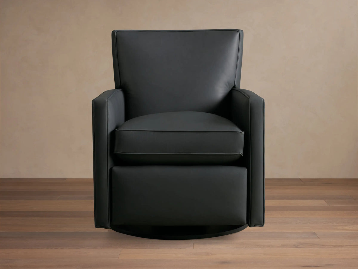 Rudy Leather Swivel Recliner, a sleek black leather armchair with thin arms, on wood floor against a neutral wall.