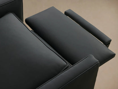 Dark gray Rudy Leather Swivel Recliner, front-facing, with piped cushions and track arms, on a wood floor.
