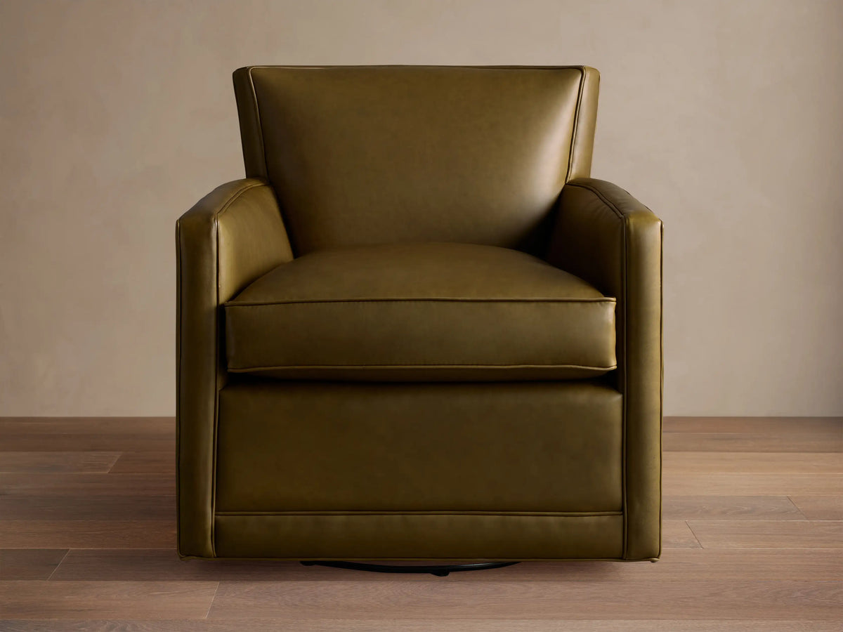 Olive green Rudy Leather Swivel Chair with a square, modern design and sleek arms, on a warm wooden floor.